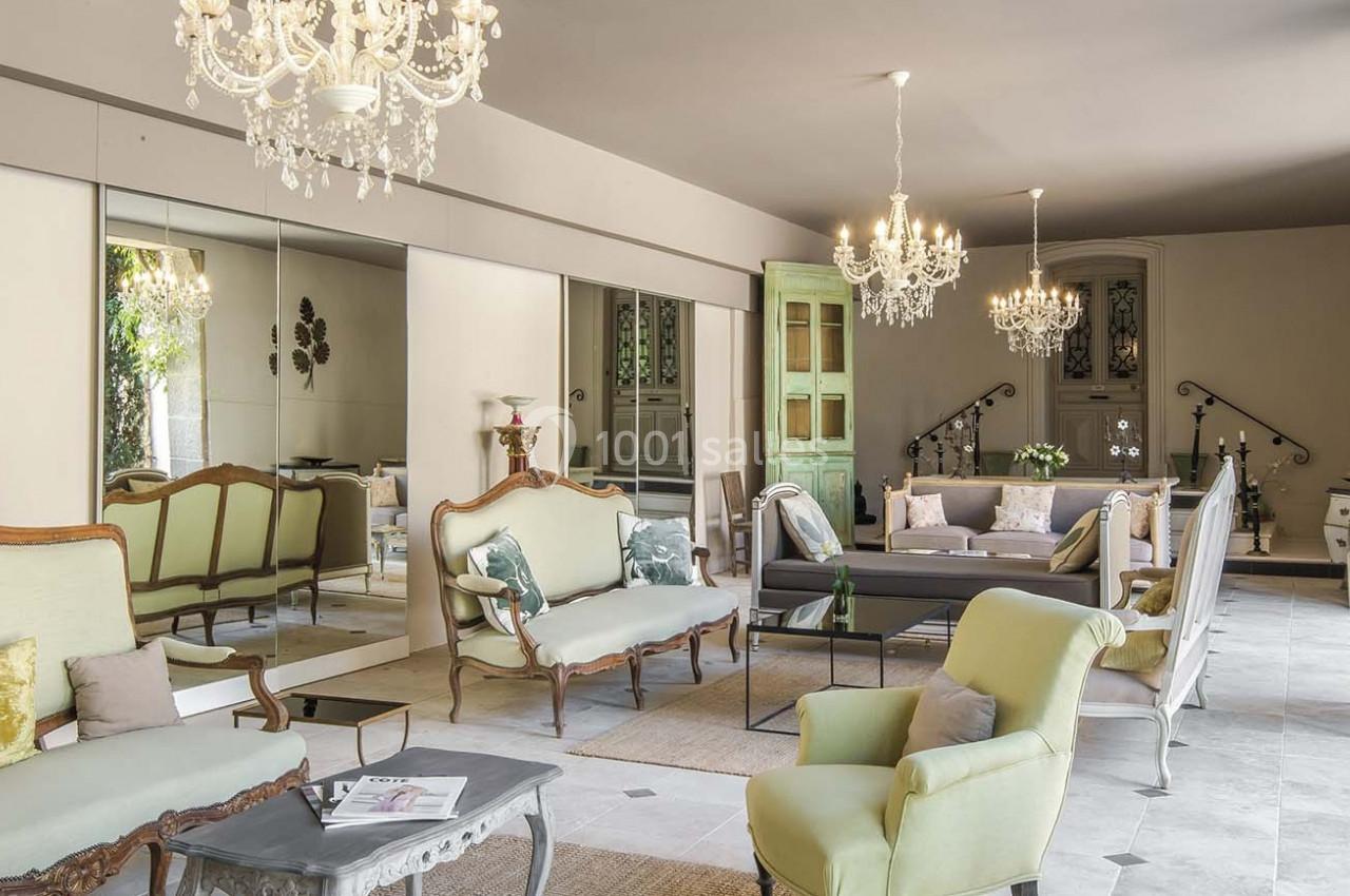 Salon élégant avec mobilier classique, lustres en cristal, miroirs muraux et lumière naturelle entrant par les fenêtres.