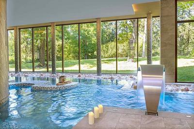 Accueil d'un spa avec comptoir en bois, fauteuils, étagère de produits, et décoration évoquant un arbre.