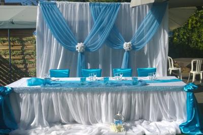 Salle de réception décorée en noir et blanc avec tables dressées, chaises blanches et lanternes suspendues.