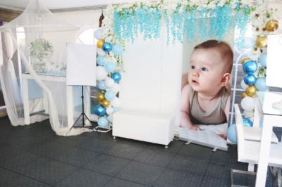 Salle de réception décorée en noir et blanc avec tables dressées, chaises blanches et lanternes suspendues.