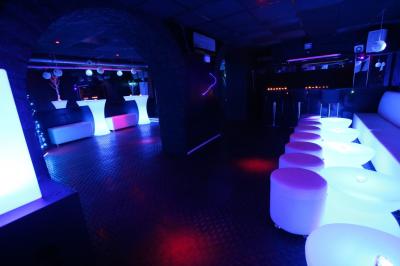 Salle de réception décorée en noir et blanc avec tables dressées, chaises blanches et lanternes suspendues.