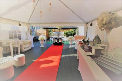 Salle de réception décorée en noir et blanc avec tables dressées, chaises blanches et lanternes suspendues.