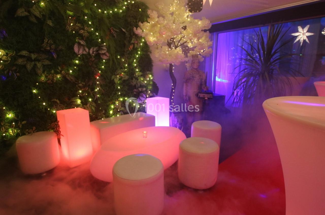 Espace lounge avec mobilier lumineux, mur végétal éclairé et ambiance tamisée avec fumée et décorations lumineuses.