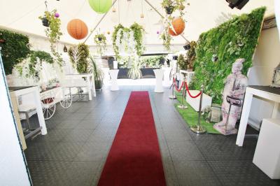 Salle de réception décorée en noir et blanc avec tables dressées, chaises blanches et lanternes suspendues.