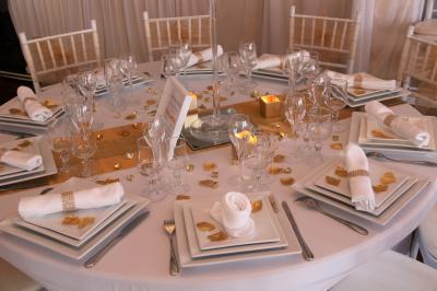 Salle de réception décorée en noir et blanc avec tables dressées, chaises blanches et lanternes suspendues.