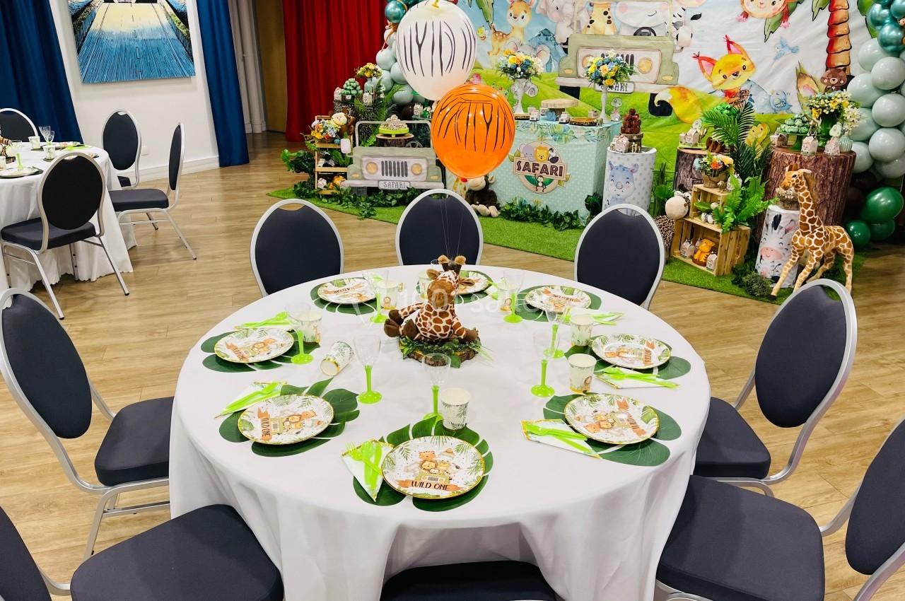 Table décorée sur le thème safari avec assiettes illustrées, serviettes vertes et centre de table en forme de girafe.