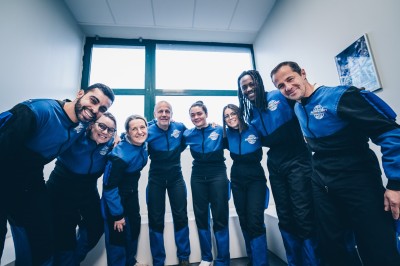 Un groupe de personnes en tenue uniforme observe et interagit avec un écran dans un environnement futuriste.