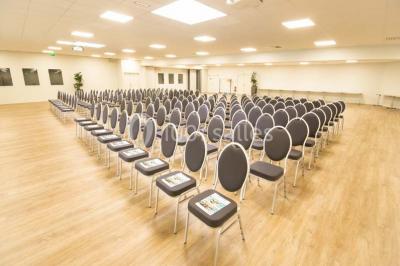 Salle de conférence vide avec des rangées de chaises noires et un écran affichant le logo ’Aerokart’.