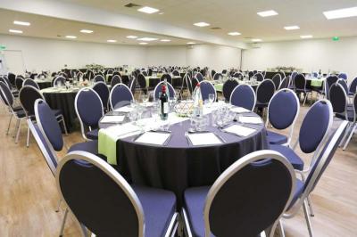 Salle de conférence vide avec des rangées de chaises noires et un écran affichant le logo ’Aerokart’.
