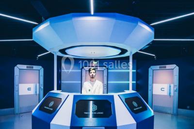 Salle de conférence vide avec des rangées de chaises noires et un écran affichant le logo ’Aerokart’.