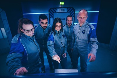 Salle de conférence vide avec des rangées de chaises noires et un écran affichant le logo ’Aerokart’.