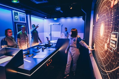 Salle de conférence vide avec des rangées de chaises noires et un écran affichant le logo ’Aerokart’.