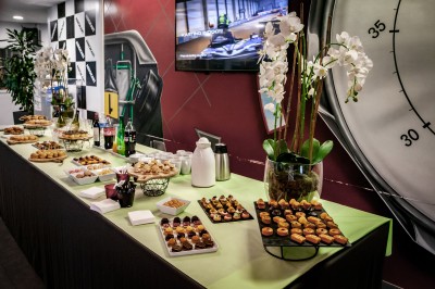 Salle de conférence vide avec des rangées de chaises noires et un écran affichant le logo ’Aerokart’.