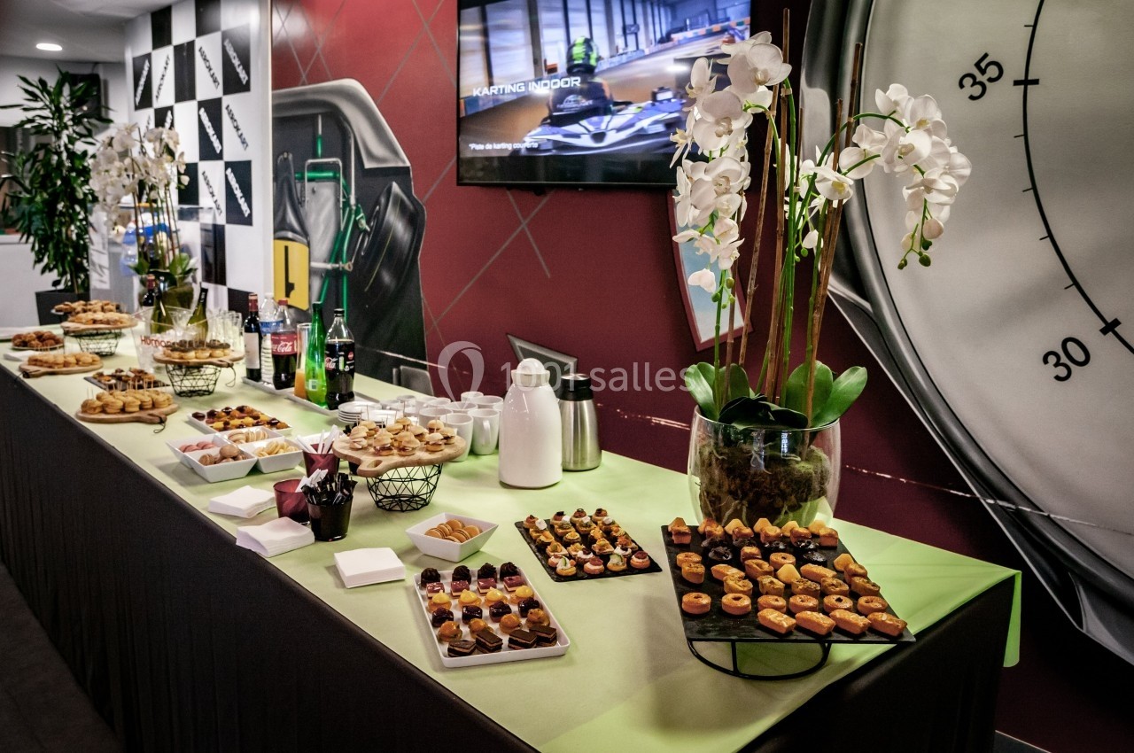 Buffet composé de petits fours, desserts, boissons et décoré avec des orchidées blanches sur une table verte.