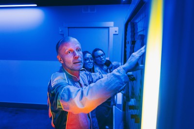 Salle de conférence vide avec des rangées de chaises noires et un écran affichant le logo ’Aerokart’.
