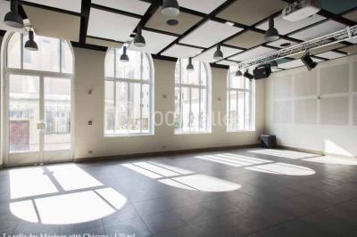 Disposition en U de tables blanches avec chaises noires dans une salle de réunion équipée d'un tableau et d'une fontaine à…