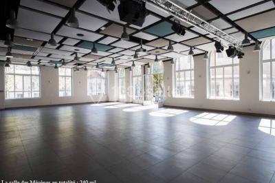 Disposition en U de tables blanches avec chaises noires dans une salle de réunion équipée d'un tableau et d'une fontaine à…