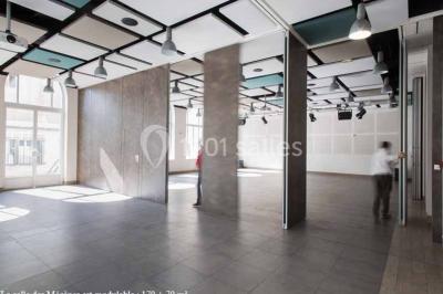 Disposition en U de tables blanches avec chaises noires dans une salle de réunion équipée d'un tableau et d'une fontaine à…