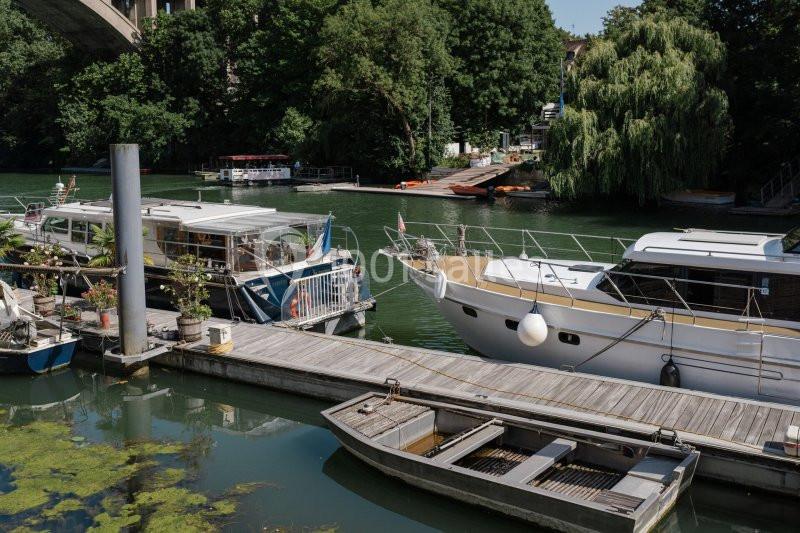 Bateaux amarrés le long d'un ponton en bois sur une rivière bordée d'arbres.