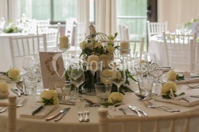 Intérieur élégant avec décorations classiques, horloge, miroir, fleurs et cage décorative dans une lumière tamisée.
