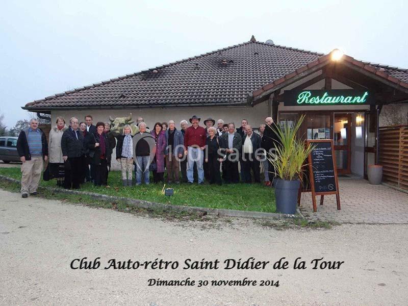 Un groupe de personnes posant devant un restaurant avec une enseigne lumineuse et un tableau noir à l'entrée.