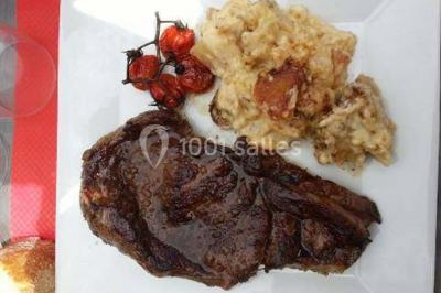 Assiette de carpaccio de bœuf garnie de salade, copeaux de parmesan, tomates et filet de sauce balsamique.