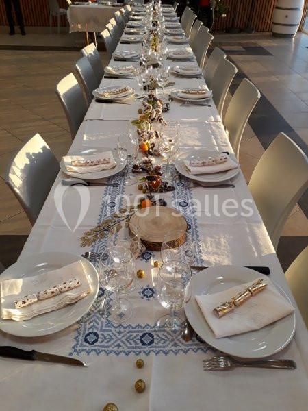 Table dressée pour un repas festif, ornée de décorations naturelles et de motifs brodés sur une nappe blanche.