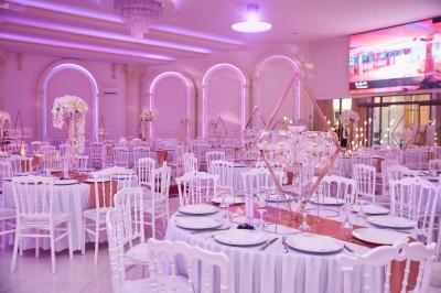 Vue aérienne d'une table élégante décorée de fleurs blanches avec des chaises dorées et un sol en marbre clair.