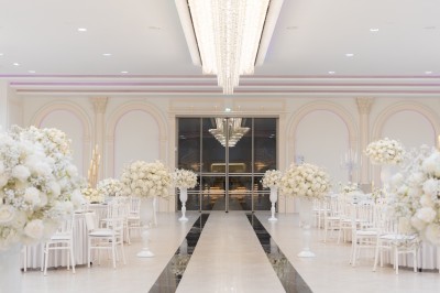 Vue aérienne d'une table élégante décorée de fleurs blanches avec des chaises dorées et un sol en marbre clair.