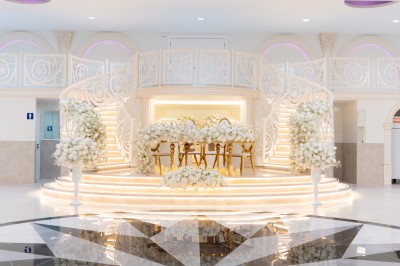 Vue aérienne d'une table élégante décorée de fleurs blanches avec des chaises dorées et un sol en marbre clair.