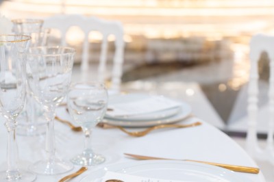 Vue aérienne d'une table élégante décorée de fleurs blanches avec des chaises dorées et un sol en marbre clair.