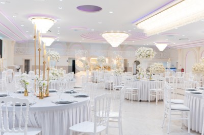 Vue aérienne d'une table élégante décorée de fleurs blanches avec des chaises dorées et un sol en marbre clair.