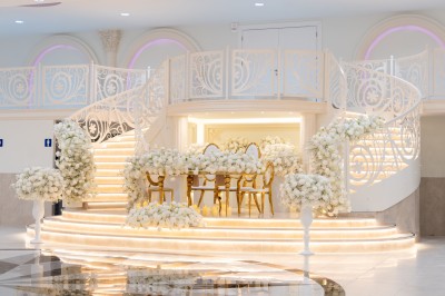 Vue aérienne d'une table élégante décorée de fleurs blanches avec des chaises dorées et un sol en marbre clair.