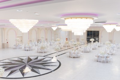 Vue aérienne d'une table élégante décorée de fleurs blanches avec des chaises dorées et un sol en marbre clair.