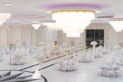 Vue aérienne d'une table élégante décorée de fleurs blanches avec des chaises dorées et un sol en marbre clair.