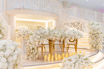 Vue aérienne d'une table élégante décorée de fleurs blanches avec des chaises dorées et un sol en marbre clair.