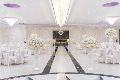 Vue aérienne d'une table élégante décorée de fleurs blanches avec des chaises dorées et un sol en marbre clair.