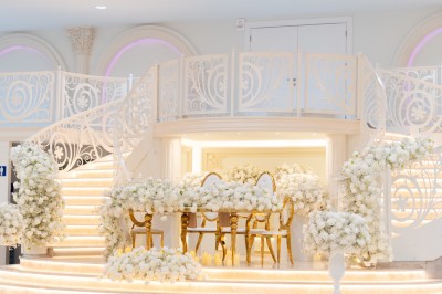 Vue aérienne d'une table élégante décorée de fleurs blanches avec des chaises dorées et un sol en marbre clair.