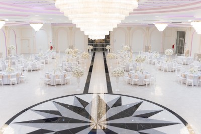 Vue aérienne d'une table élégante décorée de fleurs blanches avec des chaises dorées et un sol en marbre clair.