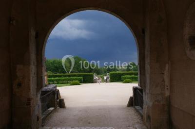 Vue aérienne d'un château entouré d'un parc, d'un étang et d'un village avec des maisons et des espaces verts.
