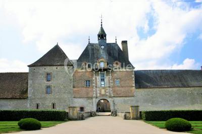 Vue aérienne d'un château entouré d'un parc, d'un étang et d'un village avec des maisons et des espaces verts.