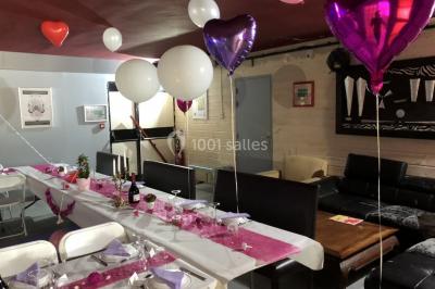 Globes décoratifs, confettis colorés et petites boîtes blanches ornées de rubans violets disposés sur une table festive.