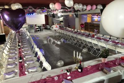 Globes décoratifs, confettis colorés et petites boîtes blanches ornées de rubans violets disposés sur une table festive.