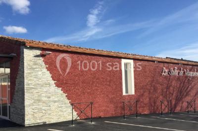 Table en inox avec étagère inférieure dans une cuisine professionnelle équipée de fours et d'équipements.