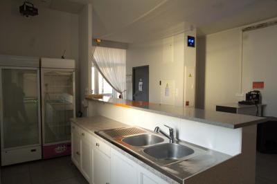 Table en inox avec étagère inférieure dans une cuisine professionnelle équipée de fours et d'équipements.