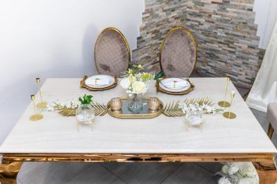 Table en inox avec étagère inférieure dans une cuisine professionnelle équipée de fours et d'équipements.