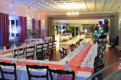 Parking extérieur vide avec un seul véhicule blanc, entouré de végétation et d'un mur en pierre.