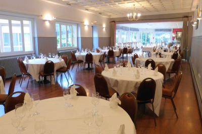 Parking extérieur vide avec un seul véhicule blanc, entouré de végétation et d'un mur en pierre.