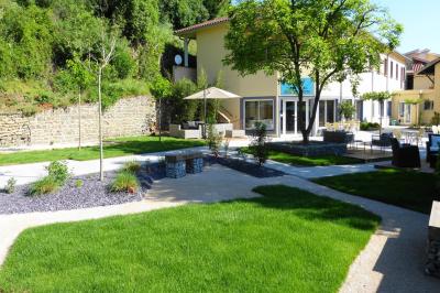Parking extérieur vide avec un seul véhicule blanc, entouré de végétation et d'un mur en pierre.