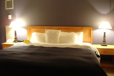 Parking extérieur vide avec un seul véhicule blanc, entouré de végétation et d'un mur en pierre.